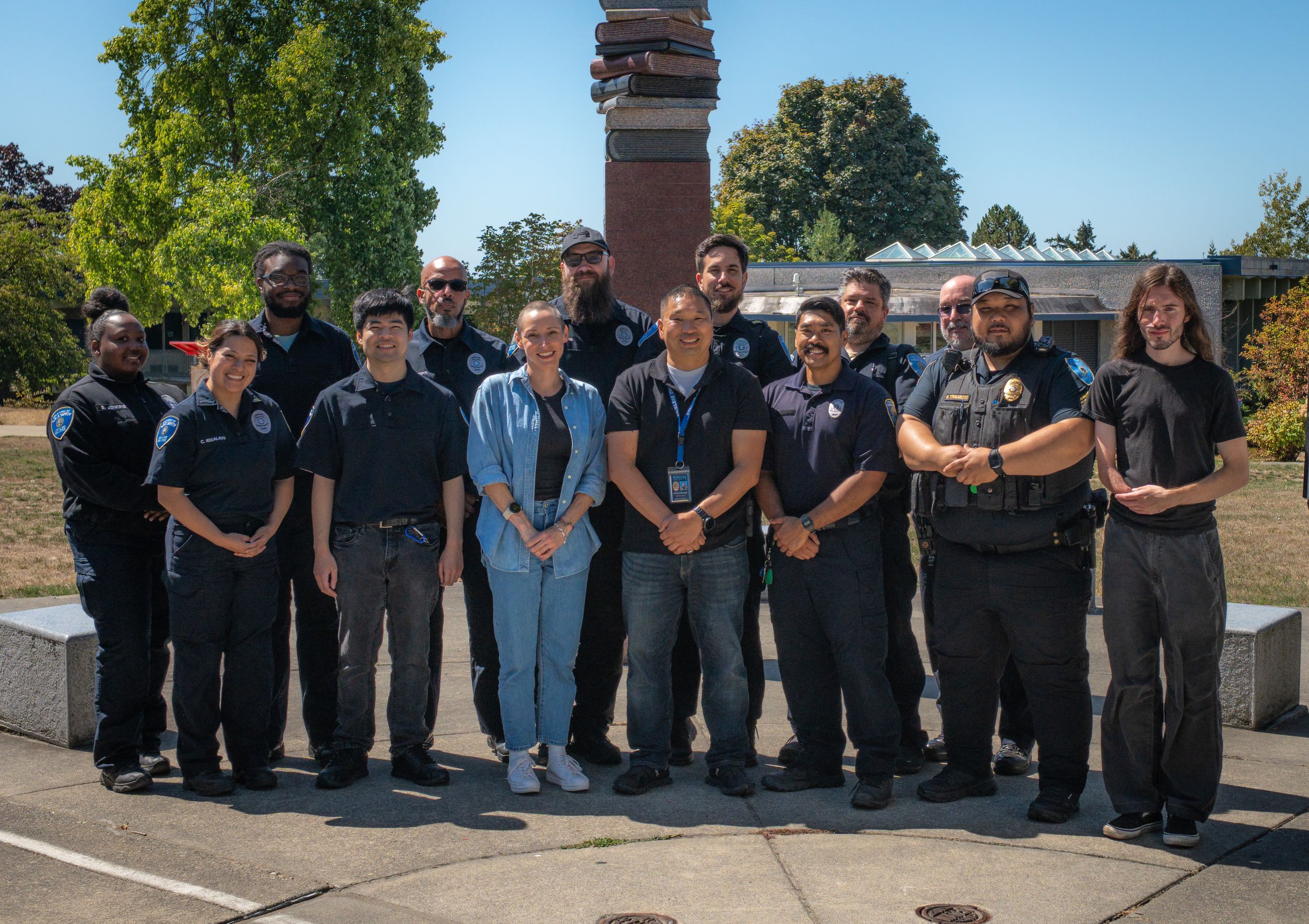 Public Safety team members standing in a group outdoors, with trees, a sculpture, and a building in the background